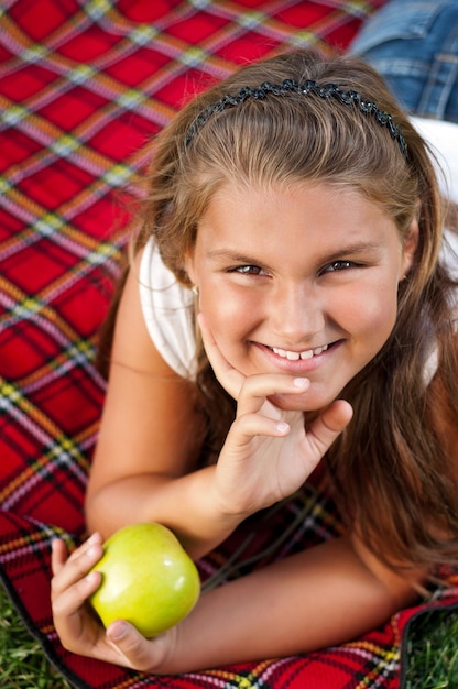 Portrait d'une petite fille avec une pomme verte en plein air