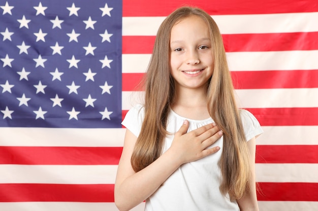 Portrait d'une petite fille qui a joint ses mains pour la prière et le drapeau de l'Amérique