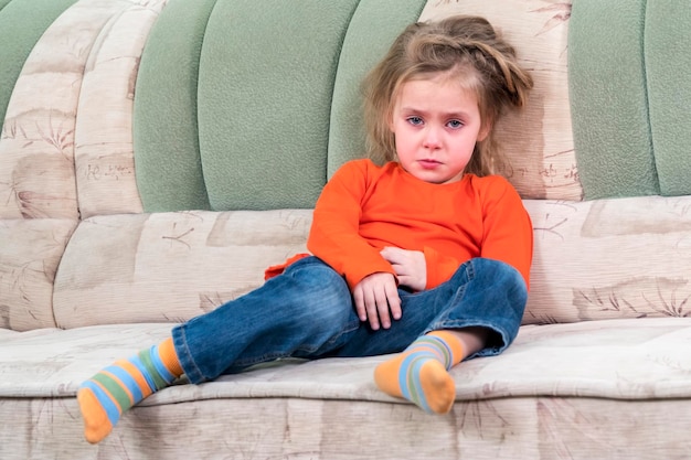 portrait d'une petite fille qui pleure assise sur le canapé