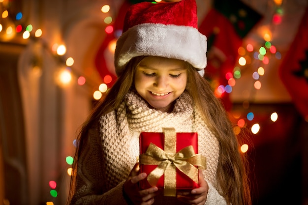 Portrait de petite fille regardant la boîte ouverte avec le cadeau de Noël