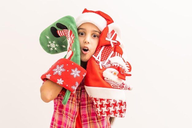 Portrait d'une petite fille riante tenant une décoration de Noël dans les mains sur fond blanc