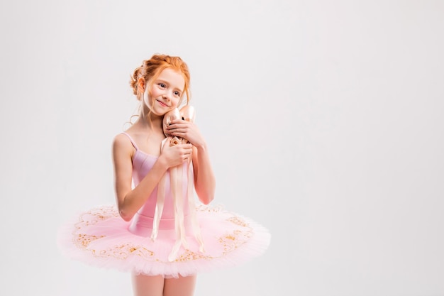 Portrait d'une petite fille rousse tendre en tutu rose avec chaussons de pointe rêvant de devenir ballerine