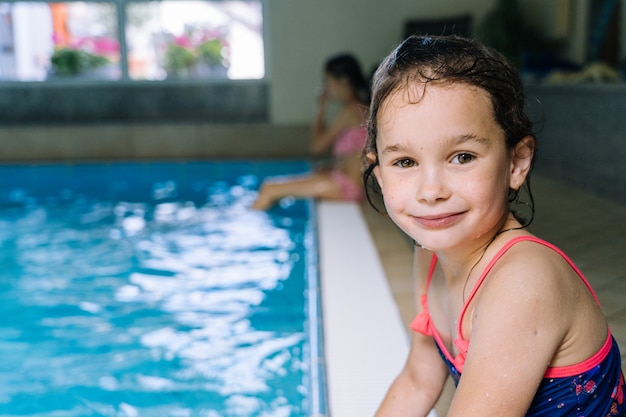 Portrait petite fille s'amuser dans la piscine intérieure.