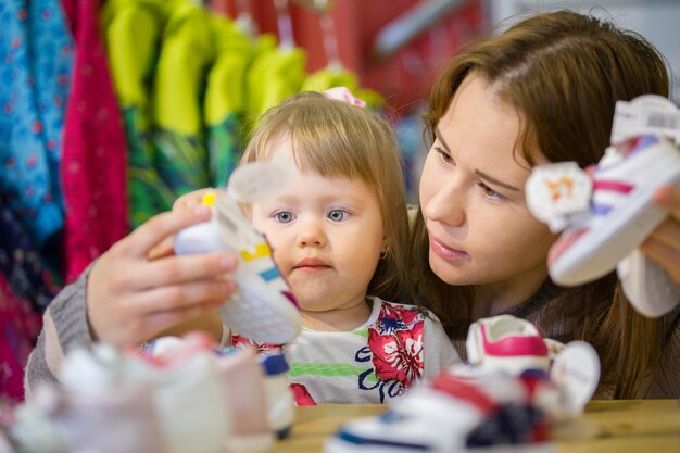 Portrait de petite fille avec sa mère choisissant des chaussures