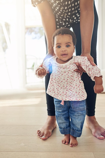 Portrait d'une petite fille souriante debout avec le soutien de sa mère