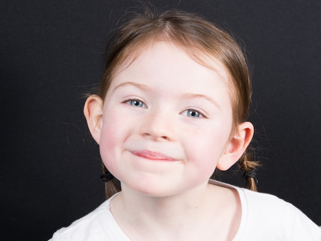 Portrait de petite fille souriante sur fond noir