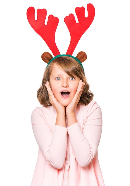 Portrait d'une petite fille surprise avec des cornes de Noël drôles d'un cerf Concept de vacances heureux enfant mignon regardant la caméra isolé sur fond blanc