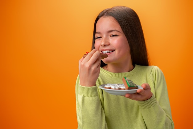 Portrait de petite fille tenant une assiette avec des biscuits sur fond orange