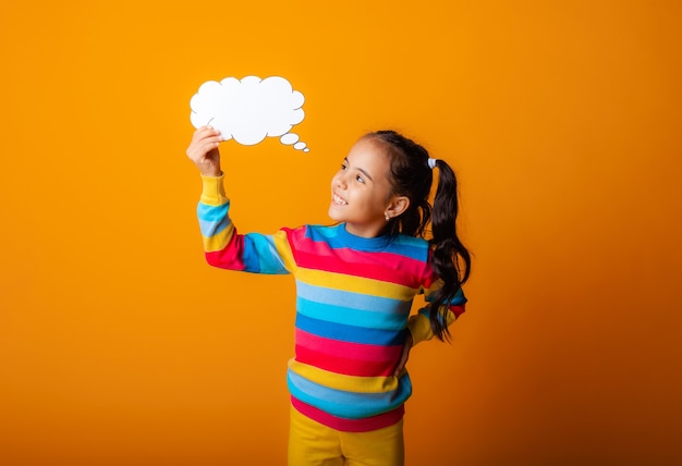 Portrait d'une petite fille tenant un nuage de papier vide méditant sur une idée.