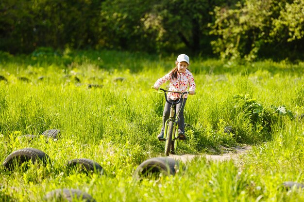 Portrait d'une petite fille à vélo dans un parc d'été à l'extérieur