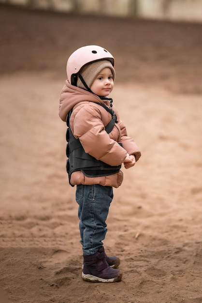 Portrait de petite fille en veste de protection et casque avant la leçon d'équitation