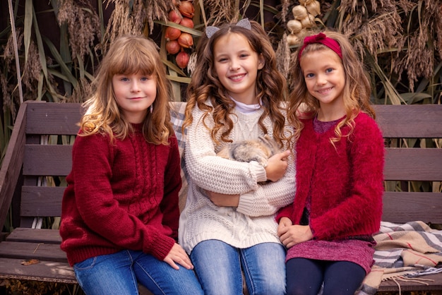 Photo portrait de petites filles copines à l'automne avec un lapin dans les mains près de leur maison fam