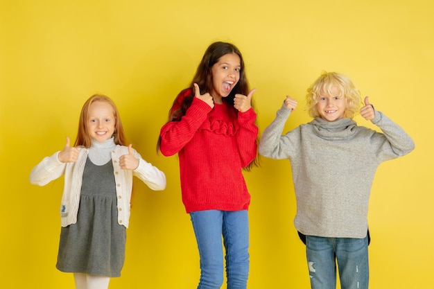 Portrait de petits enfants de race blanche avec des émotions vives isolés sur fond de studio jaune