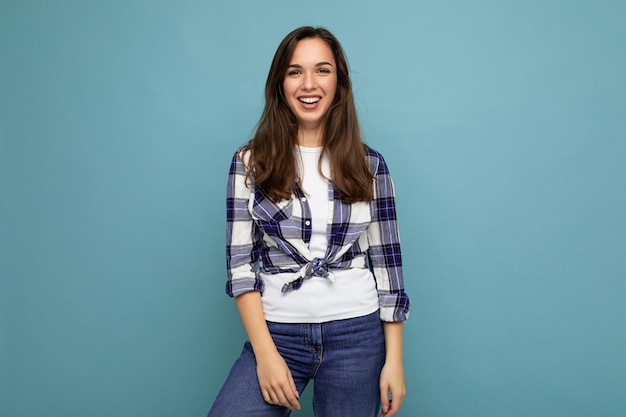 Portrait photo de la belle jeune femme brune hipster souriante en chemise bleue et blanche à la mode et