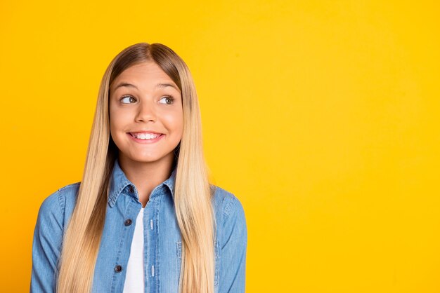 Portrait photo d'une écolière préadolescente rêveuse et drôle en train de penser à une nouvelle idée isolée sur un fond de couleur jaune vif avec un espace vide