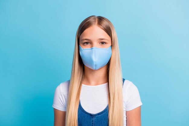 Portrait photo d'écolière souriante porter un masque antigrippal isolé sur fond de couleur bleu pastel