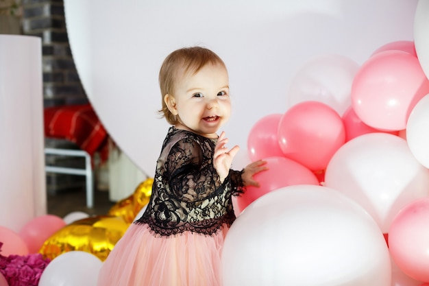 Portrait photo d'une fille d'anniversaire de 1 an dans une robe rose avec des ballons roses. L'enfant aux sourires de vacances, les émotions des enfants. Fête d'anniversaire