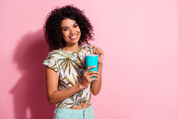 Portrait photo de fille tenant une tasse de papier paille en plastique dans les mains isolées sur fond de couleur rose pastel avec un espace vide