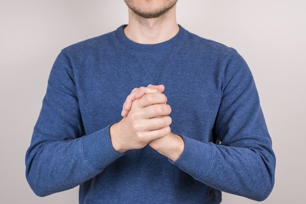 Portrait photo en gros plan recadrée d'un gars confiant et heureux fusionnant les paumes des mains ensemble fond gris isolé