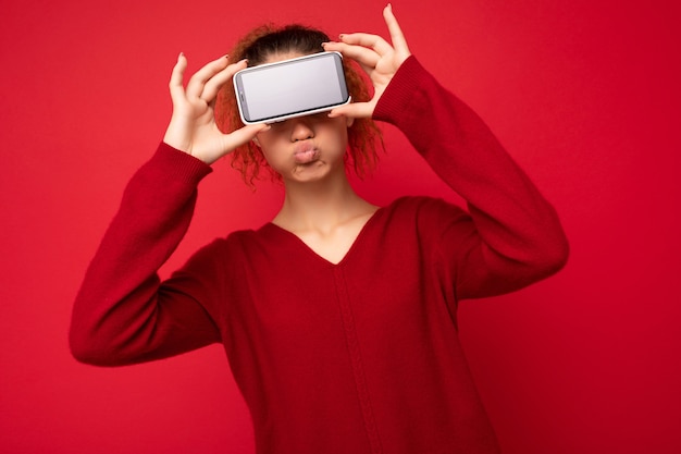 Portrait photo d'une jeune femme drôle et heureuse portant un pull rouge foncé isolé sur fond rouge