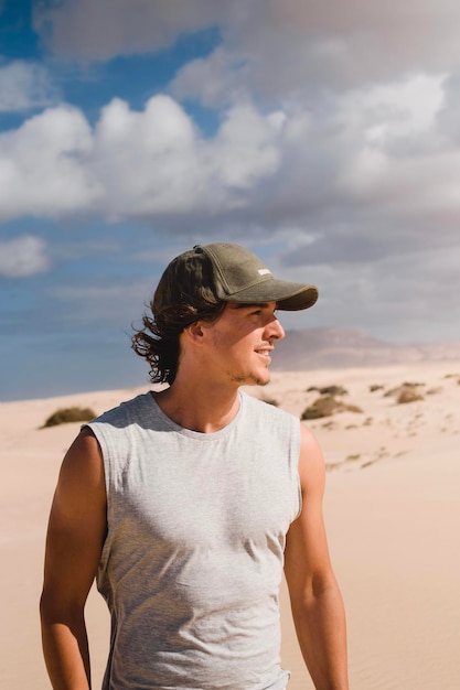 Photo portrait photo d'un jeune homme souriant dans le désert de fuerteventura en été un voyage de vacances