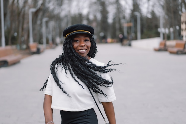 Portrait de photo de joyeuse fille à la peau noire dans un parc de la ville.