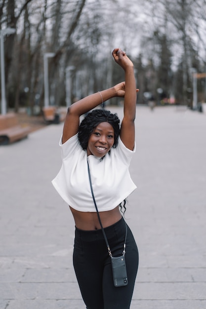 Portrait de photo de joyeuse fille à la peau noire dans un parc de la ville.