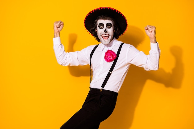 Portrait photo de joyeux fou gentil beau mec mexicain drôle en costume traditionnel levant les poings isolés sur fond jaune de couleur vive