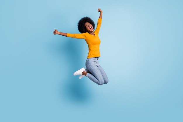 Portrait photo tout le corps d'une fille excitée célébrant le saut isolé sur fond de couleur bleu pastel