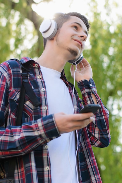 Portrait photo vertical à faible angle de vue d'un gars joyeux et excité satisfait à l'aide d'un lecteur mp3 dans les mains