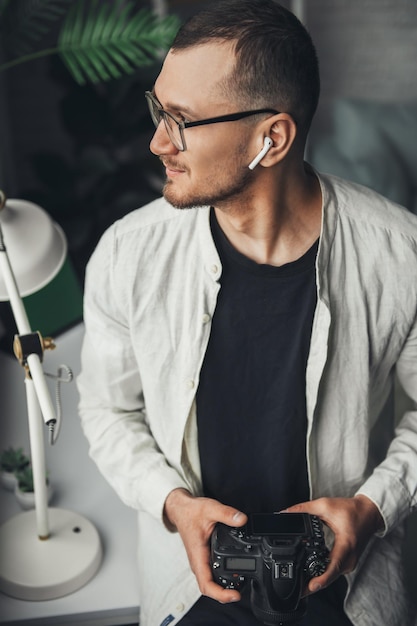 Le portrait d'un photographe tenant l'appareil photo dans ses mains et regardant d'un côté en pensant à abou