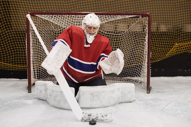 Portrait en pied du joueur de hockey féminin défendant la porte en pleine vitesse