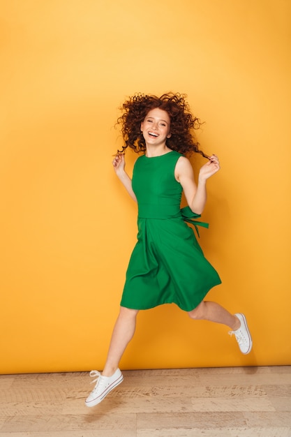 Portrait en pied d'une femme rousse heureuse en robe