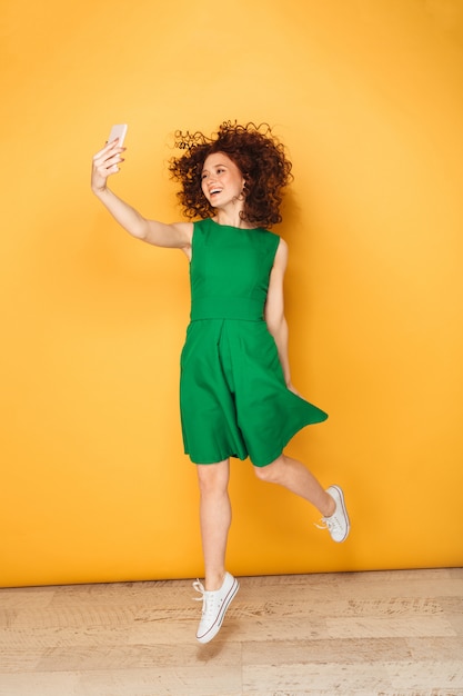 Portrait en pied d'une femme rousse joyeuse en robe