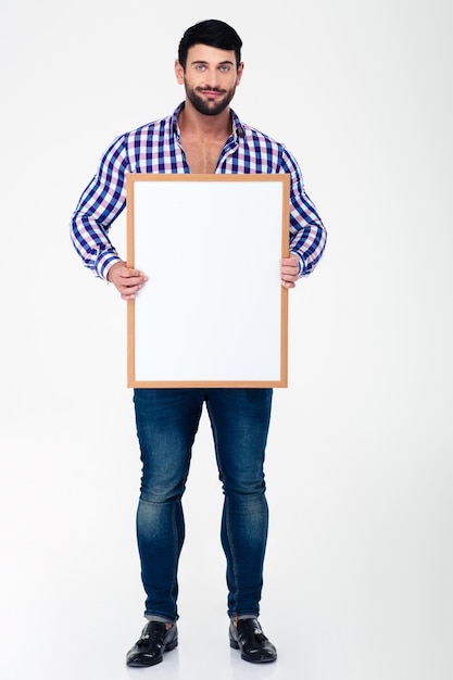 Portrait en pied d'un homme heureux tenant un tableau blanc isolé sur un mur blanc