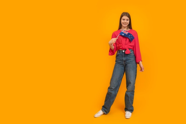 Portrait en pied d'une jeune femme avec le drapeau de l'Australie sur fond jaune Étudier dans les universités australiennes Espace réservé au texte