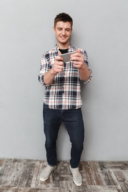 Portrait en pied d'un jeune homme souriant à jouer à des jeux