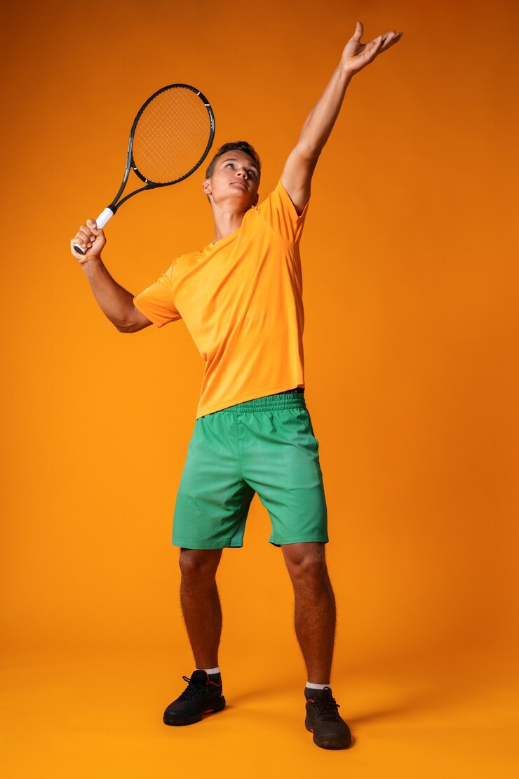 Portrait en pied d'un joueur de tennis homme en action sur fond orange close up