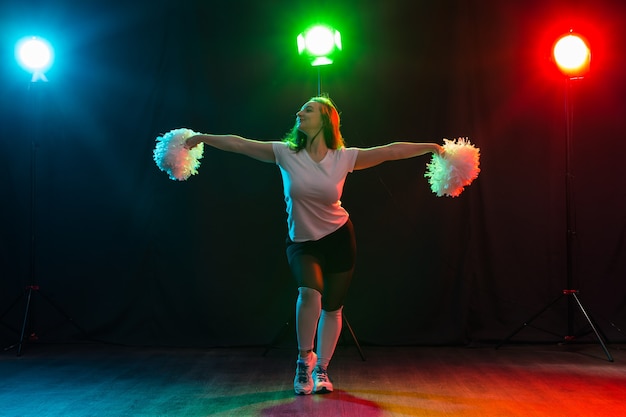 Portrait en pied d'une pom-pom girl dansant avec des pompons.