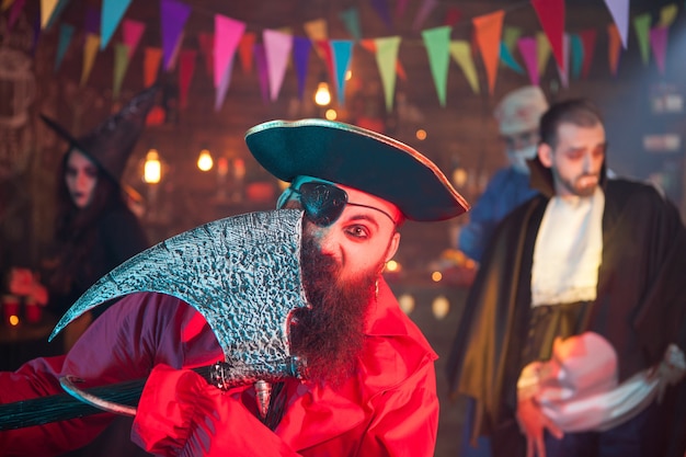 Portrait d'un pirate aux yeux avec une hache célébrant l'halloween. L'homme s'est déguisé en pirate.