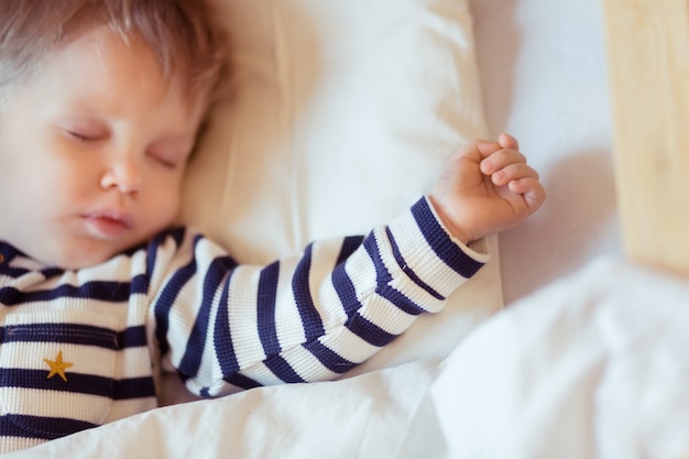 Photo portrait de plan rapproché de sommeil de bébé de 2 ans couvert de couverture blanche