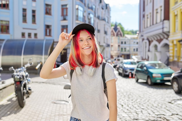 Portrait en plein air d'une adolescente souriante en bonnet noir hipster féminin à la mode avec des cheveux teints colorés dans la rue de la ville d'été ensoleillée Mode de vie jeunesse mode beauté jeunes gens concept