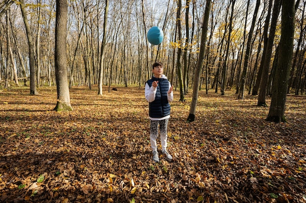 Portrait en plein air d'automne d'un garçon adolescent avec ballon de volley-ball en forêt