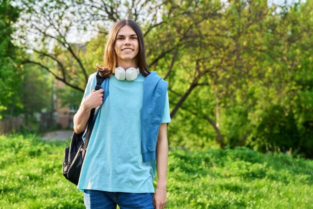 Portrait en plein air d'un beau mec étudiant avec sac à dos regardant la caméra