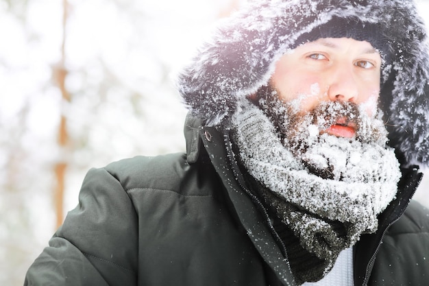 Portrait en plein air de bel homme en manteau et scurf. Homme barbu dans les bois d'hiver.