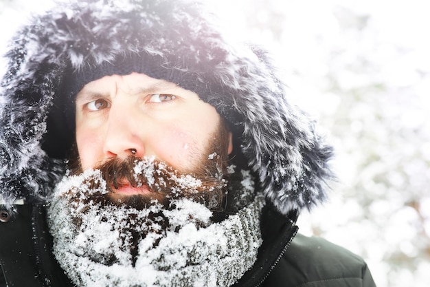 Portrait en plein air de bel homme en manteau et scurf. Homme barbu dans les bois d'hiver.