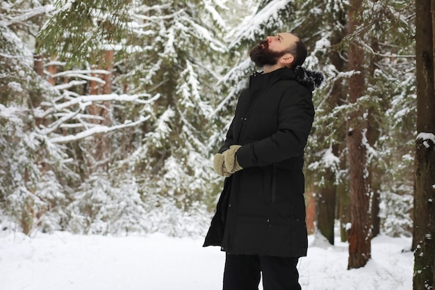 Portrait en plein air de bel homme en manteau et scurf. Homme barbu dans les bois d'hiver.