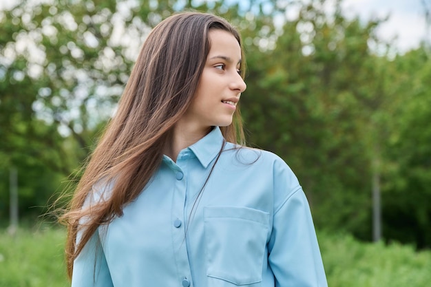 Portrait en plein air d'une belle adolescente de 15 ans souriante adolescente détournant son regard dans l'espace de copie du parc Adolescence concept d'âge scolaire