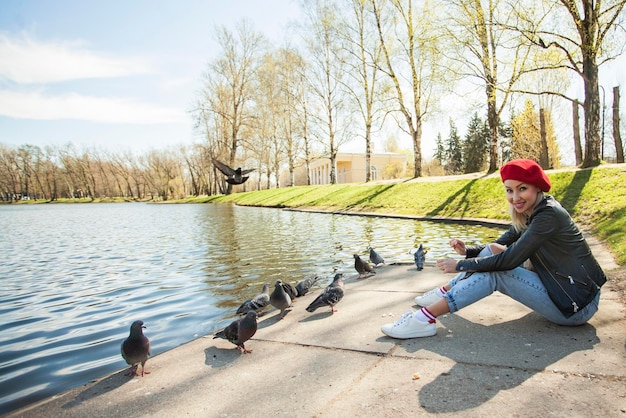 Photo portrait en plein air d'une belle jeune femme dans le parc d'une ville européenne modèle portant un béret rouge