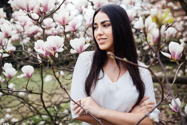 Portrait En Plein Air D'une Belle Jeune Femme Près De Magnolia Avec Des Fleurs.